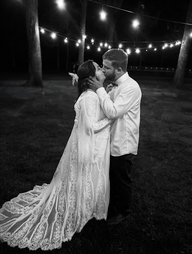 Couple kissing under string lights at rehearsal dinner